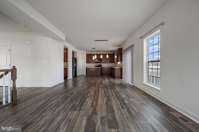 unfurnished living room with dark wood-type flooring and a chandelier