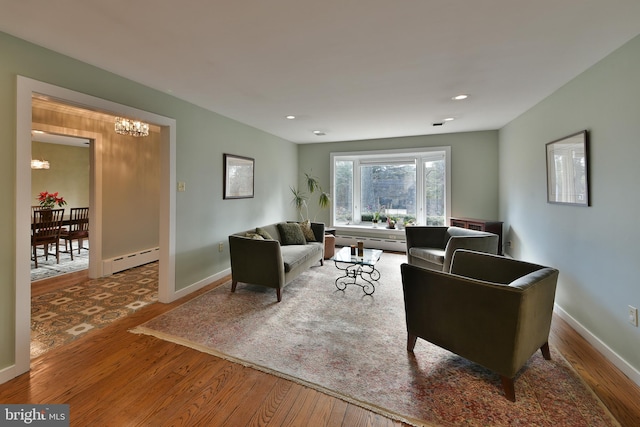 living room with a baseboard radiator, wood-type flooring, and an inviting chandelier