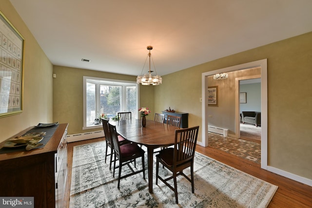 dining space featuring an inviting chandelier, hardwood / wood-style floors, and baseboard heating