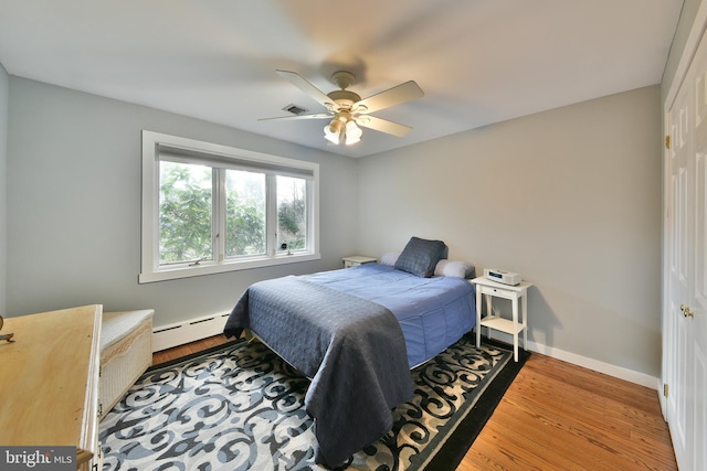 bedroom featuring a baseboard heating unit, hardwood / wood-style floors, and ceiling fan