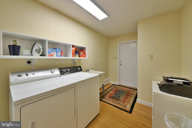 clothes washing area with independent washer and dryer, sink, and light wood-type flooring