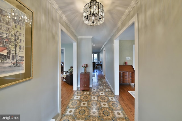 corridor with ornamental molding, wood-type flooring, and a chandelier