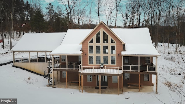 snow covered house featuring a sunroom and a deck