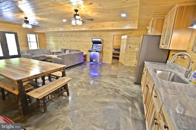 kitchen with sink, wooden ceiling, wood walls, and light brown cabinets