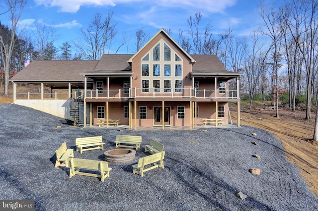 rear view of house with a wooden deck, a patio area, and a fire pit