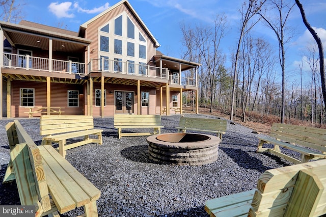 back of house featuring french doors, a balcony, a patio area, and an outdoor fire pit