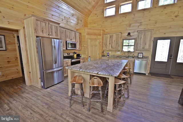 kitchen featuring appliances with stainless steel finishes, a center island, a breakfast bar area, and wooden walls