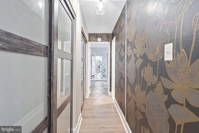 corridor featuring a textured ceiling and light wood-type flooring