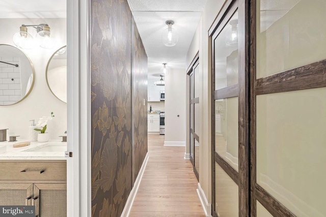 corridor with sink and light hardwood / wood-style flooring