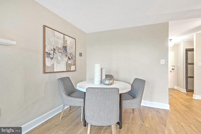 dining room featuring a textured ceiling and light hardwood / wood-style flooring