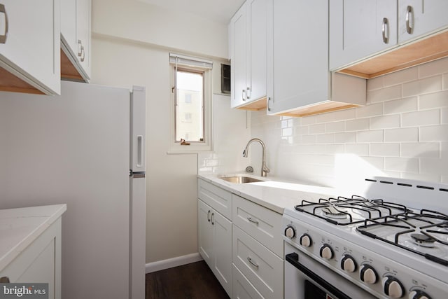 kitchen with sink, white cabinetry, white appliances, light stone countertops, and backsplash