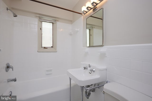 bathroom featuring tile walls, tiled shower / bath, and toilet