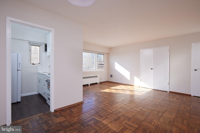 empty room with cooling unit, radiator heating unit, and dark parquet flooring