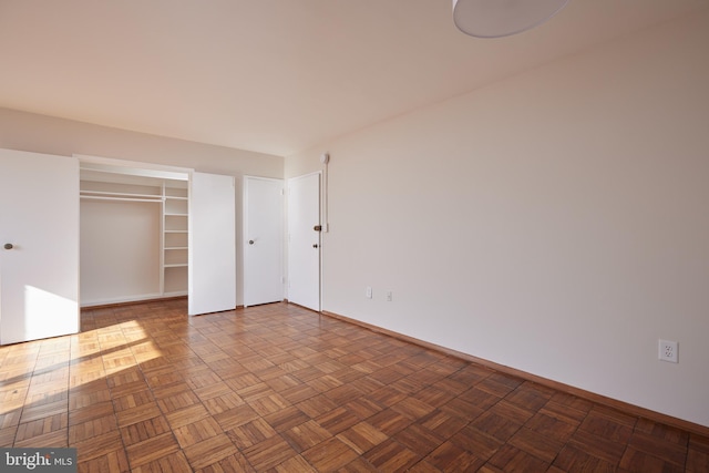 unfurnished bedroom featuring parquet floors and a closet