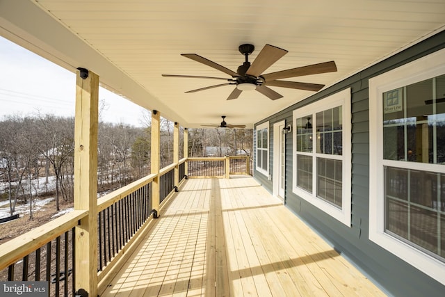 snow covered deck featuring ceiling fan and covered porch