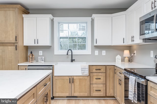 kitchen featuring white cabinetry, sink, light hardwood / wood-style flooring, and stainless steel appliances