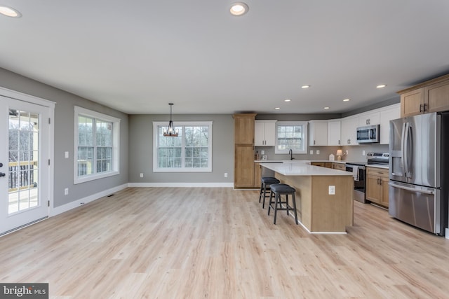 kitchen featuring sink, decorative light fixtures, a kitchen island, stainless steel appliances, and white cabinets