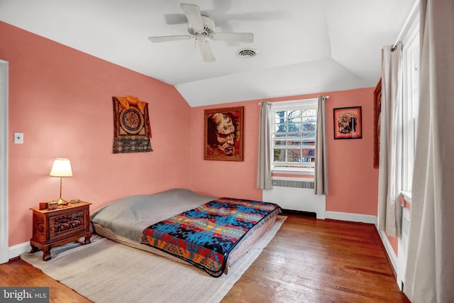 bedroom featuring hardwood / wood-style floors, vaulted ceiling, radiator, and ceiling fan