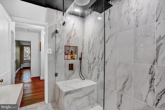 bathroom with tiled shower and hardwood / wood-style floors