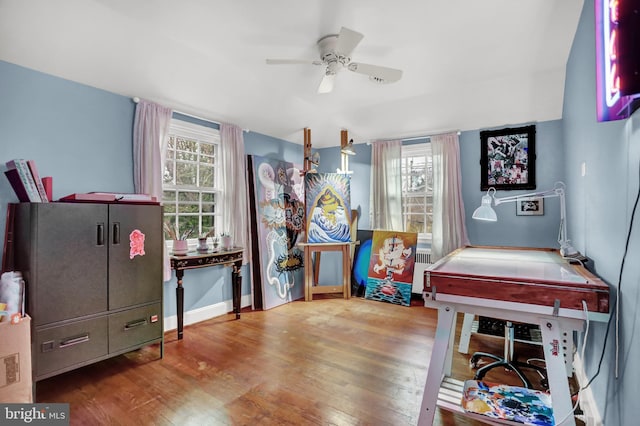 recreation room with hardwood / wood-style flooring, ceiling fan, and radiator heating unit