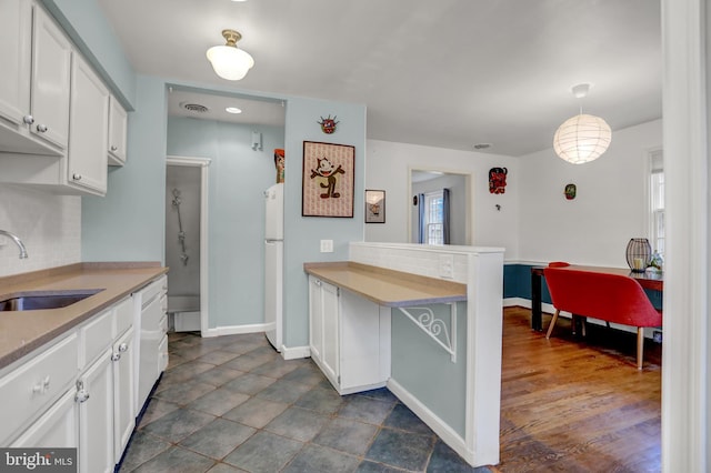 kitchen with sink, decorative light fixtures, white refrigerator, white cabinets, and backsplash