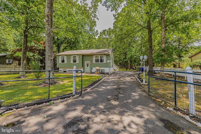 bi-level home featuring aphalt driveway, a fenced front yard, and a front yard