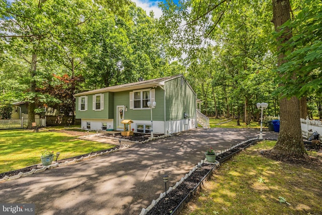 bi-level home with entry steps, a front lawn, fence, and aphalt driveway