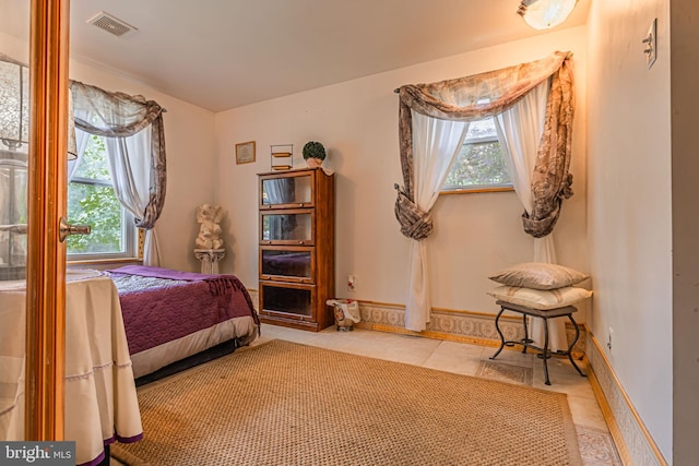 bedroom featuring multiple windows, light tile patterned flooring, visible vents, and baseboards