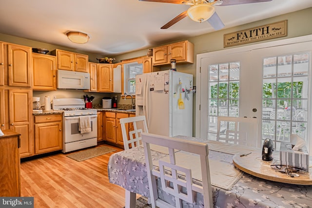 kitchen with ceiling fan, light stone counters, white appliances, a sink, and light wood finished floors