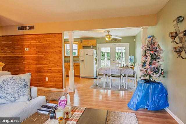 living area featuring french doors, light wood-type flooring, decorative columns, and visible vents