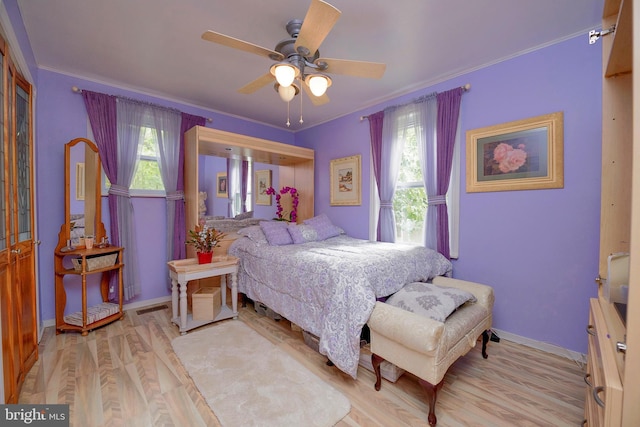 bedroom featuring ceiling fan, wood finished floors, visible vents, baseboards, and ornamental molding