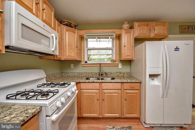 kitchen with light wood-style floors, white appliances, a sink, and light stone countertops