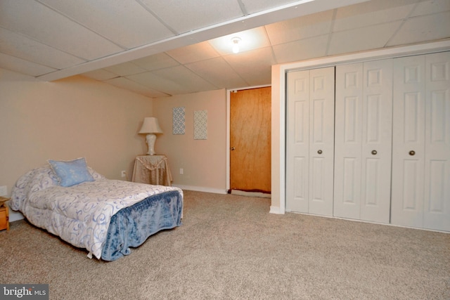 carpeted bedroom featuring a closet, a drop ceiling, and baseboards