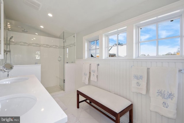 full bathroom with a wainscoted wall, a stall shower, a sink, tile patterned flooring, and lofted ceiling