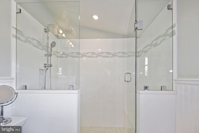 bathroom featuring lofted ceiling, wainscoting, and walk in shower