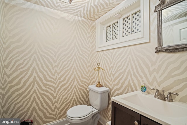 bathroom with wallpapered walls, toilet, and vanity