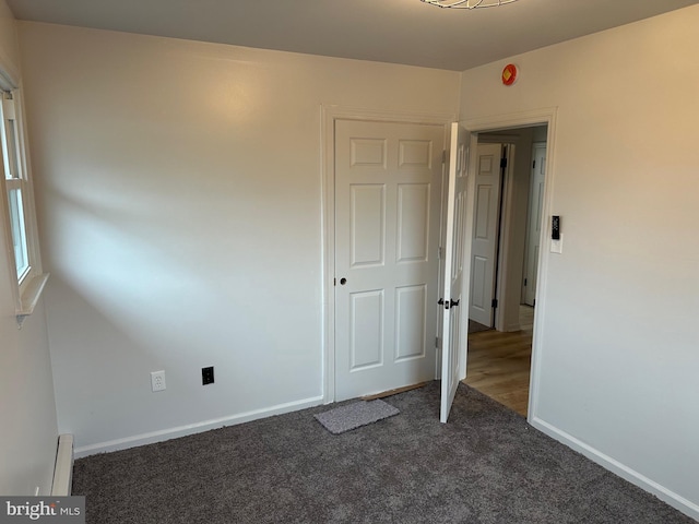 unfurnished bedroom with a baseboard radiator and dark colored carpet