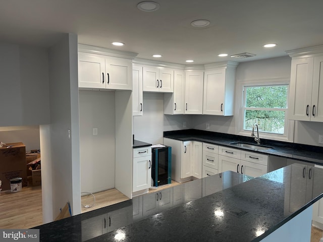 kitchen with white cabinetry, sink, dark stone countertops, beverage cooler, and light hardwood / wood-style floors