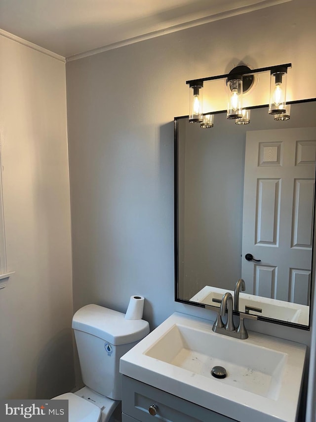 bathroom with vanity, ornamental molding, and toilet