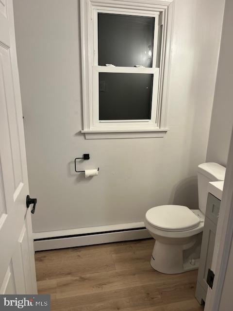 bathroom featuring hardwood / wood-style flooring, a baseboard radiator, and toilet