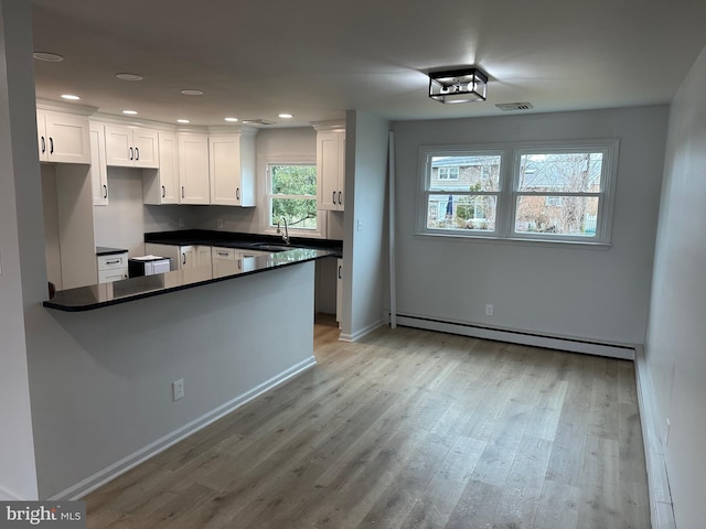 kitchen with a baseboard radiator, sink, light hardwood / wood-style flooring, and white cabinets