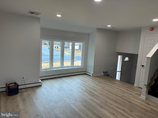 unfurnished living room featuring baseboard heating and light wood-type flooring