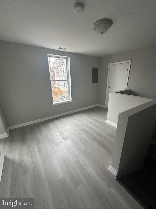 empty room featuring electric panel and light hardwood / wood-style flooring