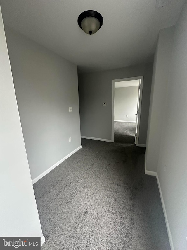 spare room with dark carpet