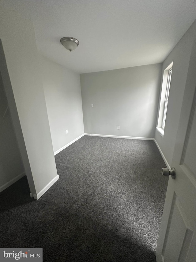 unfurnished room with dark colored carpet