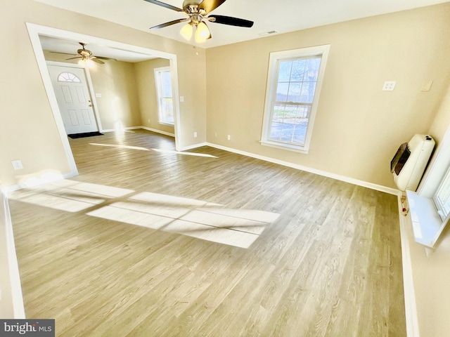 empty room featuring a healthy amount of sunlight, light hardwood / wood-style floors, and heating unit