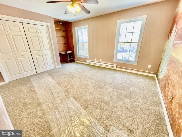 unfurnished bedroom featuring carpet flooring, a closet, ceiling fan, and baseboard heating