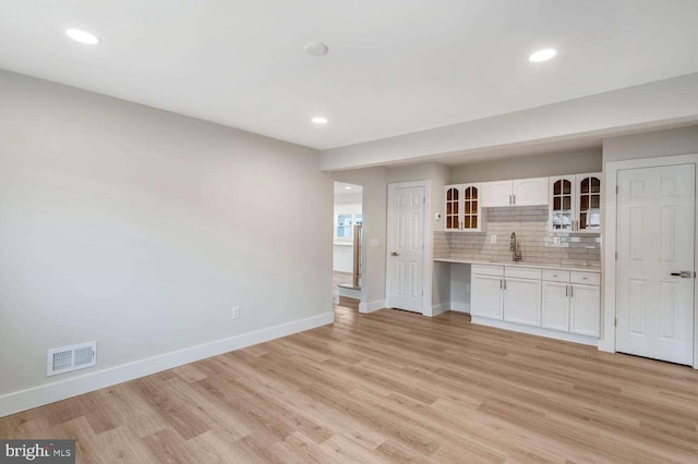 unfurnished living room with sink and light hardwood / wood-style flooring