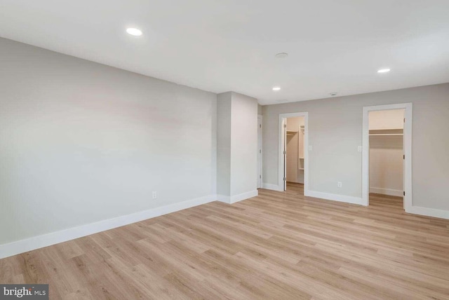 unfurnished bedroom featuring a walk in closet, light hardwood / wood-style floors, and a closet