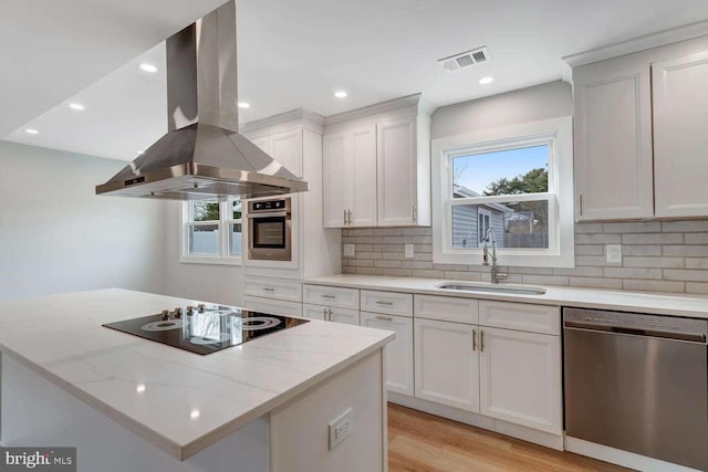 kitchen featuring sink, stainless steel appliances, light stone counters, island range hood, and white cabinets